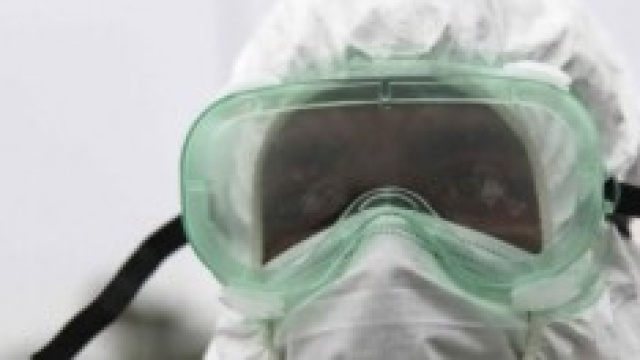 Un' infermiera con maschera e tuta protettiva. 