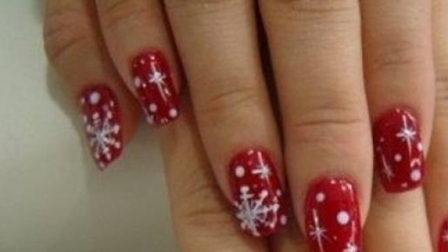 Nail art color rosso con stelline natalizie.