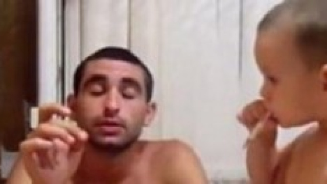 Il padre passa la sigaretta accesa al figlio 