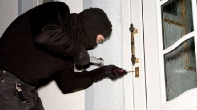 Un ladro che forza una porta di casa