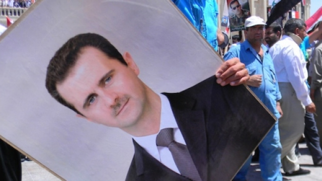 Un manifestante con la foto di Assad
