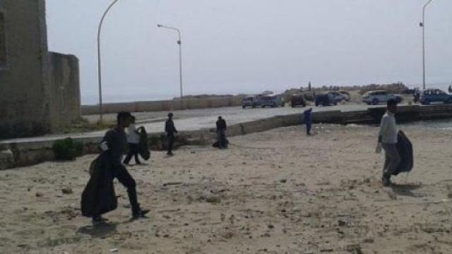 Immigrati intenti a pulire la spiaggia