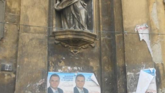 Un muro su cui campeggiano manifesti abusivi