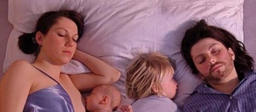 Una pareja con sus hijos en la cama