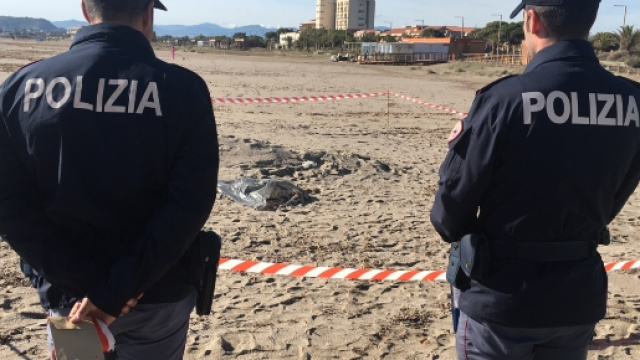 polizioti nel luogo del ritrovamento che guardano la busta al cui interno si trova il cadavere