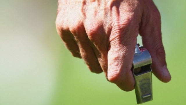 La mano di un arbitro con un fischietto