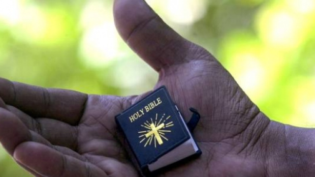 Una Bibbia in miniatura nella mano di un uomo