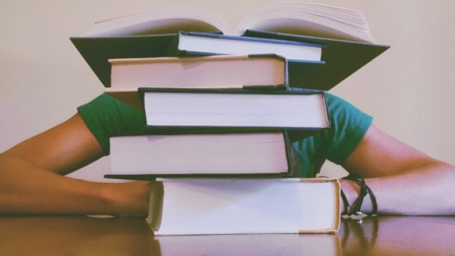 Uno studente dorme dietro una colonna di libri