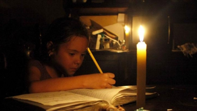 Una bambina scrive a lume di candela