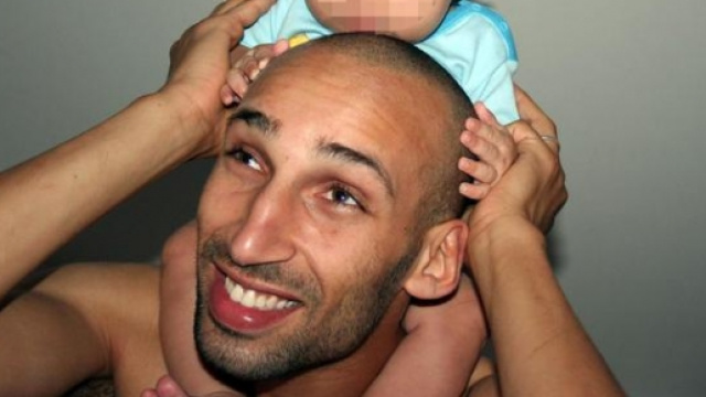 Il terrorista arrestato, mentre porta sulle spalle il figlio pi&ugrave; piccolo