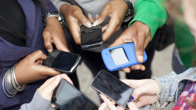 Un gruppo di ragazzi intenti a leggere i propri cellulari