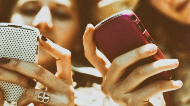 Due studentesse che chattano con i propri smartphone