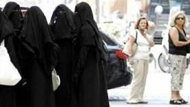 Un gruppo di donne in niqab separato da un gruppo di donne occidentali