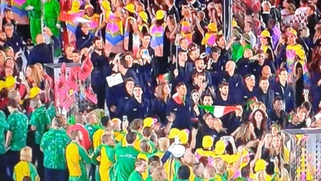 Pubblico in piedi al passaggio della squadra dei Rifugiati