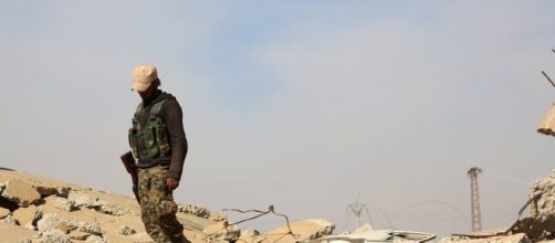 A US-backed fighter treads on rubble left by conflict inside Syria / nytimes.com