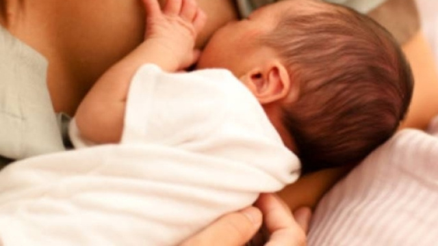 Un neonato mentre prende il latte materno