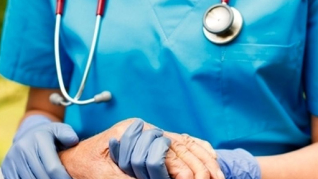 Un'infermiera mentre tiene la mano di un paziente