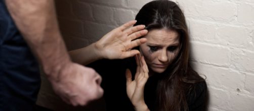 A woman covers her face for protection against a clenched fist - photo posed. Photo Credit: stopdomesticviolence.com