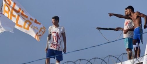 Reeducandos portando arma branca e bandeiras com palavras de ordem