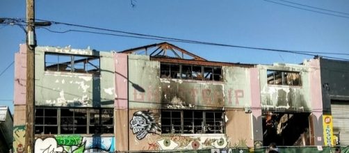 A mourner views tributes left at burned-out artists' live/work space in Oakland, Calif., where 36 died on Dec. 2 (Photo: Jim Heaphy/Wikimedia Commons)