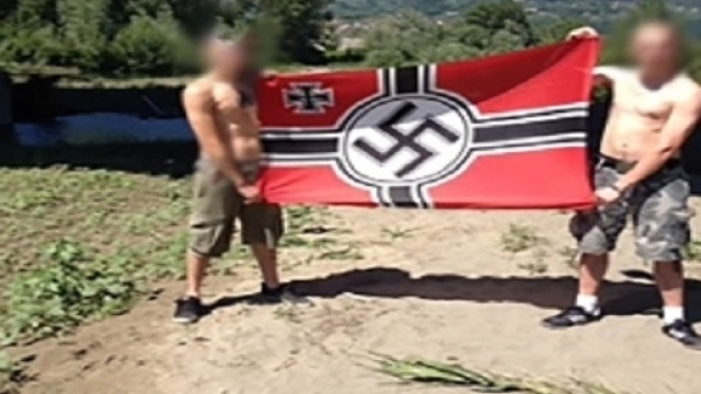 Due componenti del gruppo neonazista con una bandiera del terzo reich