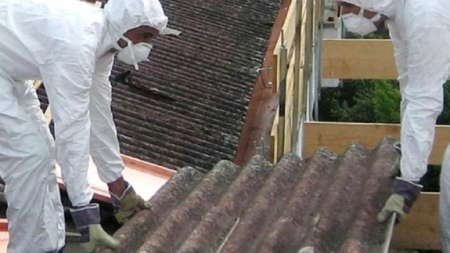 Due uomini al lavoro mentre rimuovono materiale dove &egrave; presente amianto
