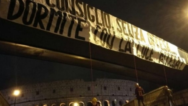 Lo striscione e i manichini appesi nei pressi del Colosseo a Roma. Foto Twitter
