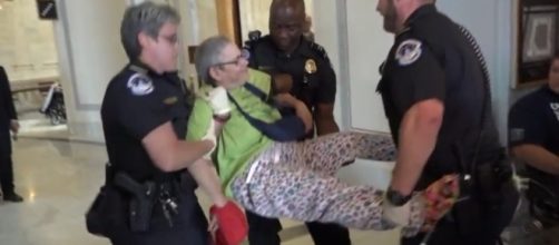 Disabled protester carried away from front of Mitch McConnel's office / Image screenshot CBS News via YouTube:https://youtu.be/qX_olozjUU8