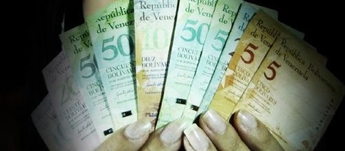 En la imagen, una mujer con billetes en la mano desplegados