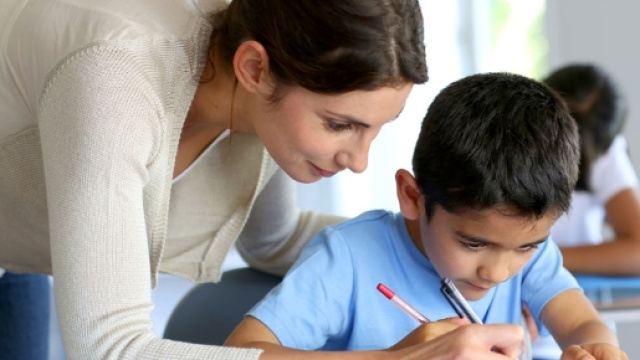 Bambino che fa i compiti a scuola con la maestra