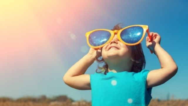 Bambina con occhiali sotto il sole accecante