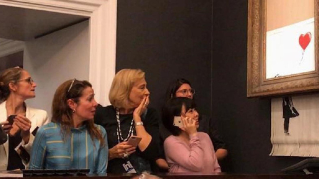 Banksy, forse nascosto tra il pubblico, mette in azione il meccanismo che seziona la tela - immagine tratta da independent.co.uk