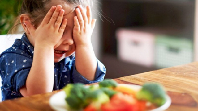 Una bambina davanti ad un piatto di verdure