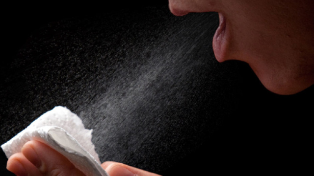 Una donna starnutisce su un fazzoletto