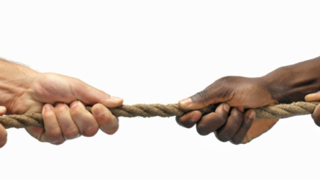 Un uomo bianco e uno nero intenti a tirare una corda