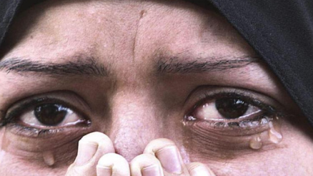 In alto, una donna musulmana incline al pianto