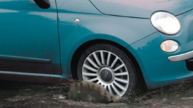 Automobilista che incorre in una buca per strada