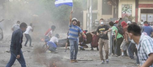 Un manifestante pone en alto la bandera nicarag&uuml;ense durante los disturbios.