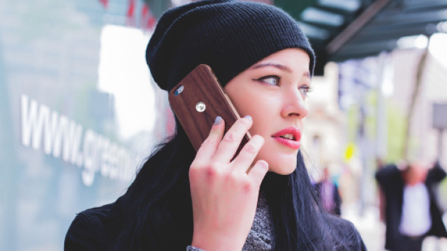 Ragazza cammina con il telefono appoggiato alla testa nonostante le avvertenze dei produttori di telefonini