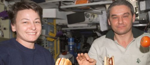 ISS astronauts eating a meal in the Service Module with tomato and hamburger floating (Image credit &ndash; NASA, Wikimedia Commons)