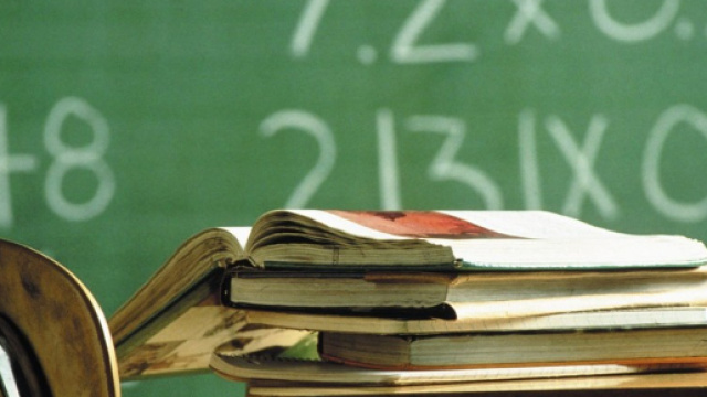 Libri su un banco di scuola e una lavagna