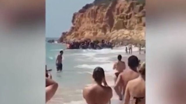Barca carica di migranti arriva sulla costa spagnola in mezzo ai turisti di un resort di lusso. (Ph. Youtube)