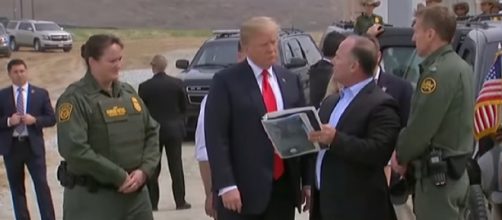 Trump examines border wall prototypes in California. [Image source/Guardian News YouTube video]