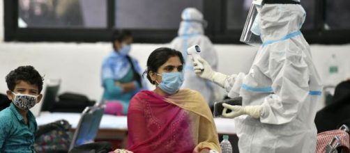 Un sanitario toma la temperatura a una mujer en India