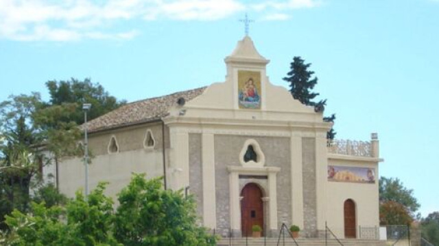 Il bianco Santuario di Manipuglia, con l'icona della Madonna rossa, blu ed oro, &egrave; avvolto dal verde degli alberi e dall'azzurro del cielo.