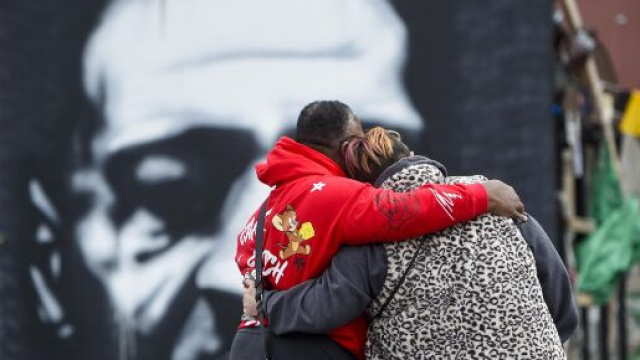 Due persone si stringono di fronte al murales dedicato a George Floyd.