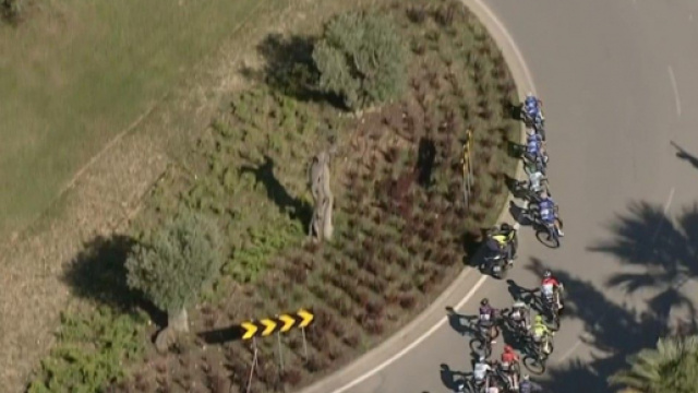 Una moto cerca di superare i corridori in una rotonda alla Volta Algarve.
