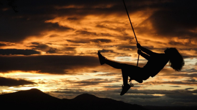 Figura femminile sull'altalena con tramonto sullo sfondo &copy; Pixabay