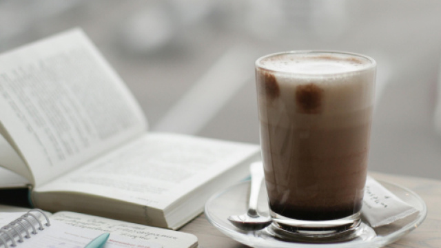 Libro con penna e cappuccinosu scrivania- &copy; Pexels