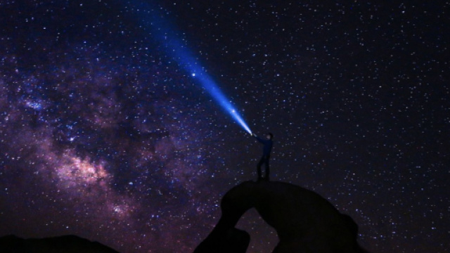 Uomo con una torcia sotto le stelle - &copy; Pixabay.